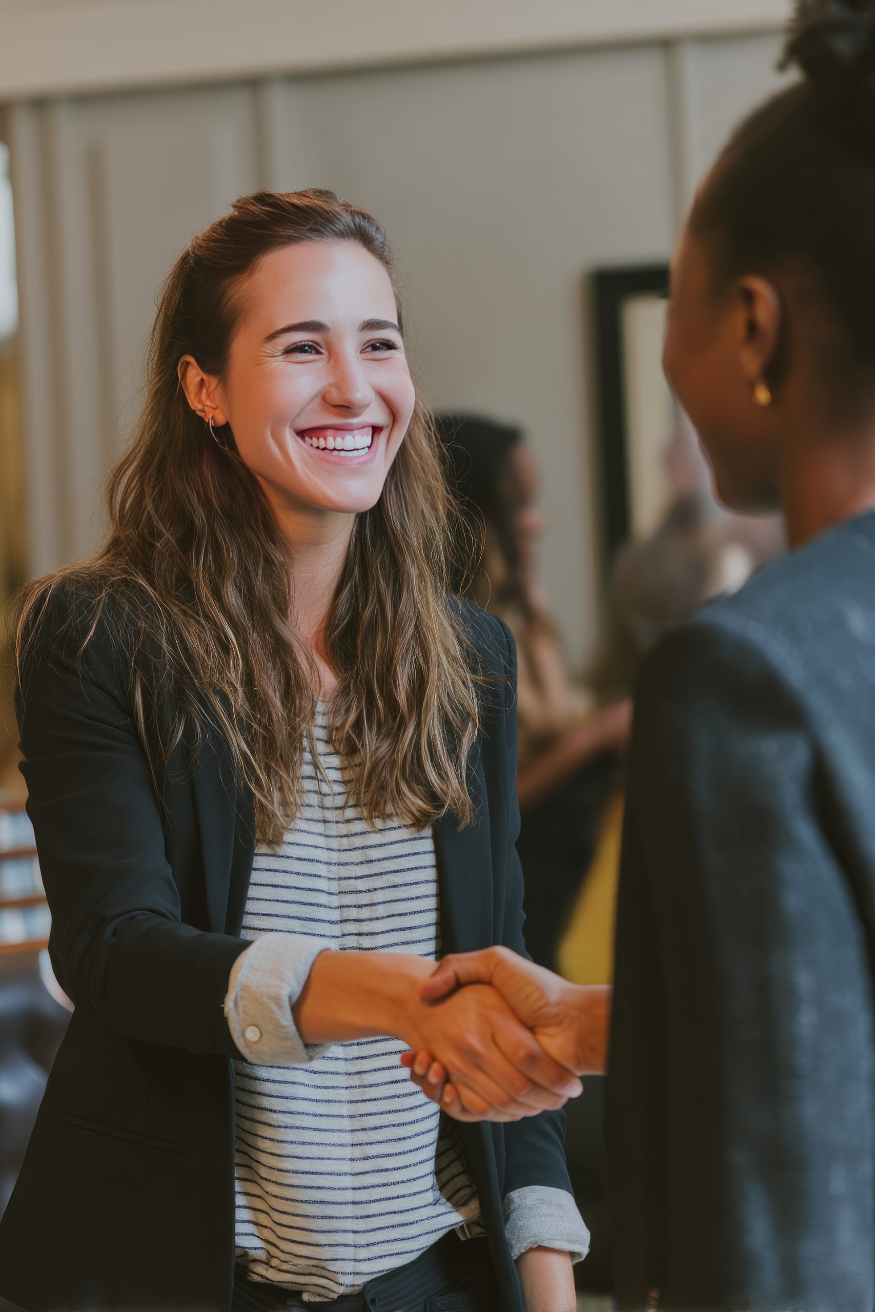 woman shaking another woman's hand because of employee benefits